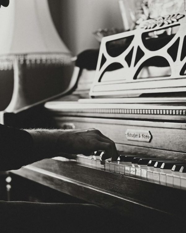 greyscale photo of man playing spinet piano close-up photo